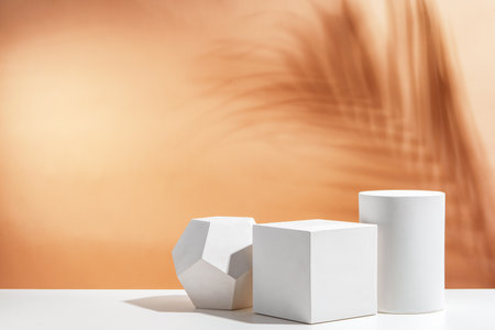 White geometric shapes arranged stylishly on a soft peach background in a minimalist settingの写真素材