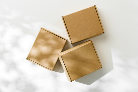 Three brown cardboard boxes arranged on a light surface with soft shadows