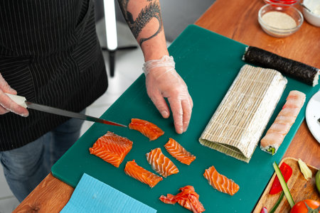 Chef preparing fresh salmon for sushi at a culinary workshop in a modern kitchenの写真素材