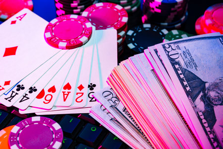 Game chips and cash on a dimly lit keyboard during an exciting gaming night at homeの写真素材