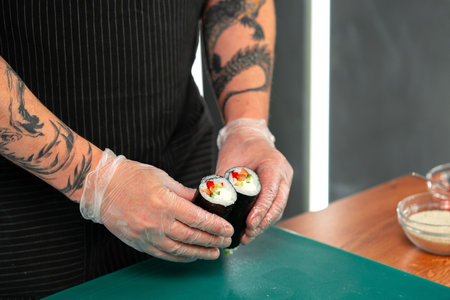 A chef prepares sushi rolls with colorful ingredients on a kitchen counter in a modern cooking spaceの写真素材