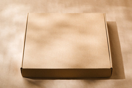 A plain cardboard box on a textured surface with soft light and shadows during the afternoonの写真素材