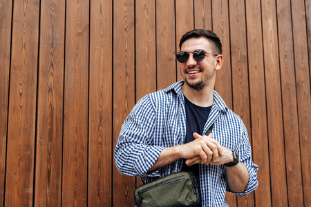 A man in a blue checkered shirt smiles while standing outside on a sunny dayの写真素材