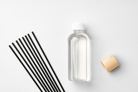 A minimalist display of essential oil and black diffuser sticks on a clean white backgroundの写真素材
