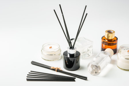 Aromatic essentials including scented candles, incense sticks, and diffusers arranged on a light...