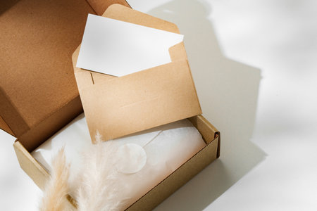 Delivery package with a blank envelope and decorative elements on a light backgroundの写真素材