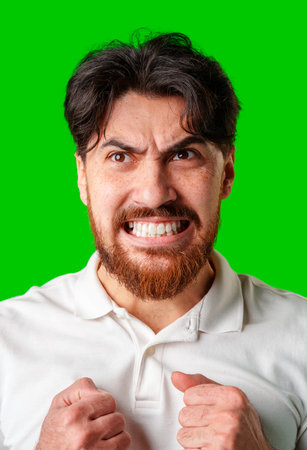 A man expresses intense frustration with a furious gesture against a bright green backdropの写真素材