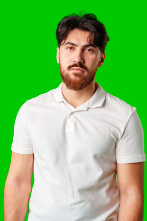 A man with a serious expression stands against a vibrant green backgroundの写真素材