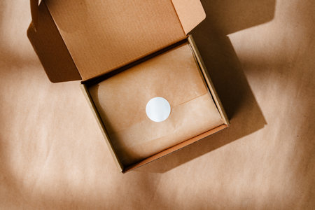 A sealed kraft box containing a wrapped item, positioned on a textured brown surface for an unboxing experienceの写真素材