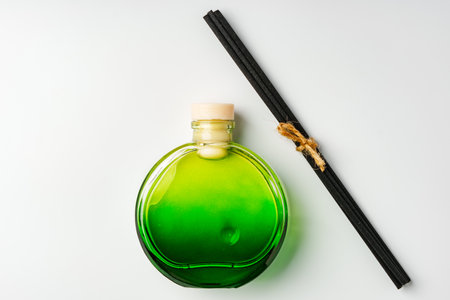 A minimalist display of essential oil and black diffuser sticks on a clean white background
