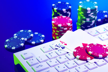 A vibrant arrangement of poker chips and playing cards on a gaming keyboard with a mouse at an...