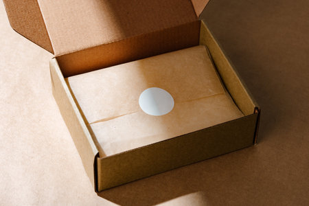 A sealed kraft box containing a wrapped item, positioned on a textured brown surface