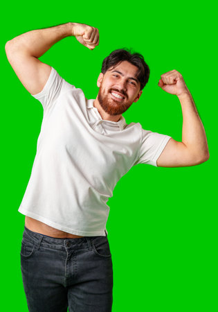 Happy man celebrating success with raised fists, wearing a white shirt against a bright green...