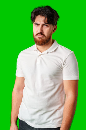 A man with a serious expression stands with crossed arms against a vibrant green backgroundの写真素材