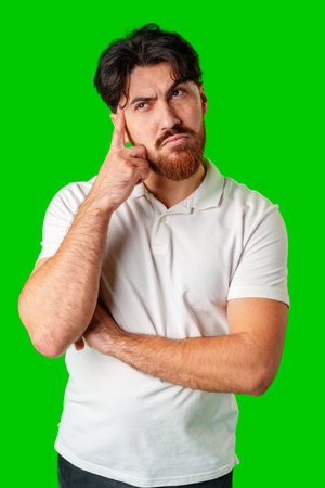 A man contemplates thoughtfully against a bright green backgroundの写真素材