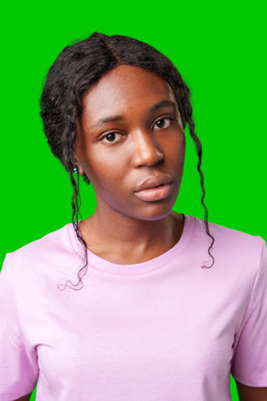 Young woman with an expression of contemplation poses against a bright green backgroundの写真素材