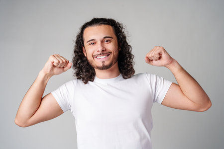 Happy man celebrating success with raised fists in a studio against a plain background