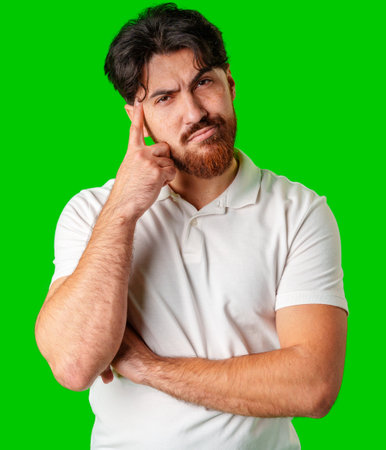 A man contemplates thoughtfully against a bright green backgroundの写真素材
