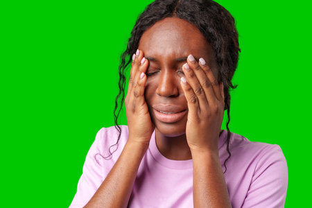 Woman expressing frustration while standing against a bright green backgroundの写真素材