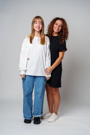 Two women standing together, one in white and the other in black, showcasing a warm connection