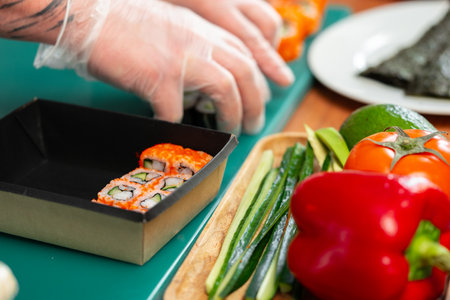 Freshly made sushi rolls with colorful vegetables sitting on a green cutting boardの写真素材