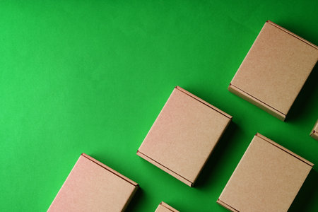 Brown cardboard boxes arranged on a vibrant green surfaceの写真素材