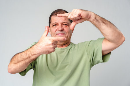 A man demonstrates framing a shot with his hands in a studio settingの写真素材