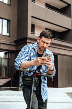 Young man enjoying a sunny day while riding an electric scooter through a modern urban settingの写真素材