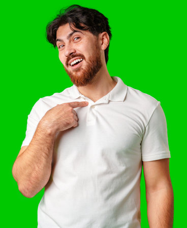 Smiling man in a white polo shirt standing confidently against a bright green backgroundの写真素材
