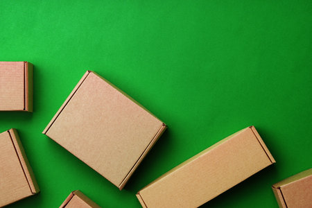 Brown cardboard boxes arranged on a vibrant green surfaceの写真素材