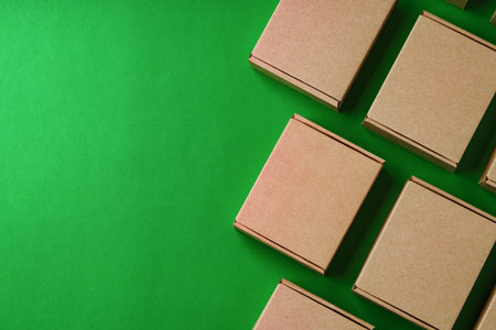 Brown cardboard boxes arranged on a vibrant green surfaceの写真素材