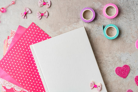 Creative supplies for scrapbooking and crafting on a textured surface with decorative tape and heart confettiの写真素材