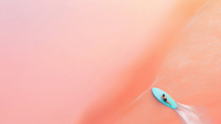 A lone surfer riding a vibrant pink wave at sunrise along the tranquil shorelineの素材