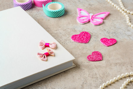 Creative supplies for scrapbooking and crafting on a textured surface with decorative tape and heart...