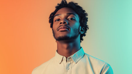 A young man poses confidently against a vibrant gradient background showcasing warm orange and cool teal huesの素材