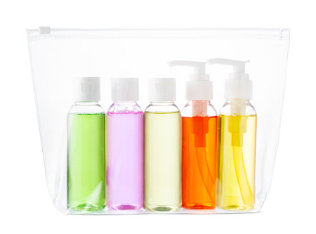 A clear travel pouch filled with vibrant toiletry bottles isolated on whiteの写真素材