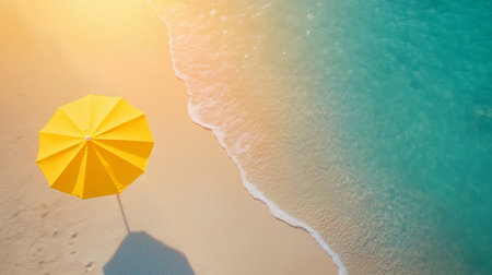 Bright yellow umbrella stands on sandy beach beside gentle waves on a sunny dayの素材