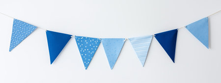 Colorful blue bunting decorations hanging for a festive event in a bright indoor space during the daytimeの素材