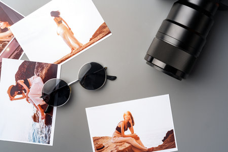 Photo camera with colorful printer photos on gray deskの写真素材