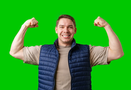 Man celebrating with raised fists in front of a bright green backgroundの写真素材