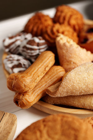 Assorted traditional pastries displayed on a wooden plate during a festive gatheringの写真素材