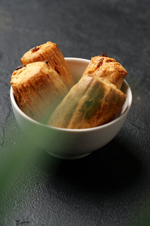 Unique natural wood pieces arranged in a small bowl resting on a textured dark surfaceの写真素材