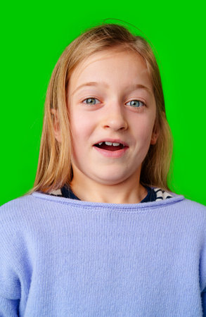 A young girl expresses surprise while smiling, with bright green backgroundの写真素材
