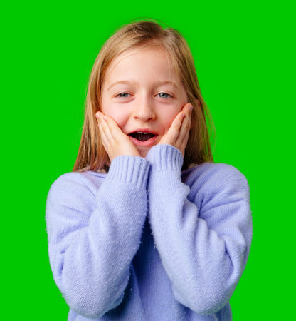 A young girl expresses surprise while smiling, with bright green backgroundの写真素材