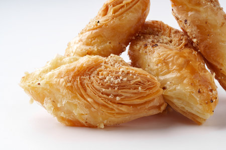 Crispy pastry dessert filled with nuts and syrup showcased on a white background during a culinary presentationの写真素材