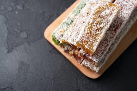 Delicious nut and fruit bars coated in coconut on a wooden platter showcasing a healthy snack optionの写真素材