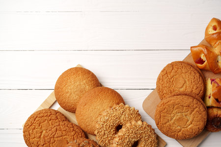 Assortment of freshly baked cookies and pastries on wooden trays in a cozy kitchen setting during...