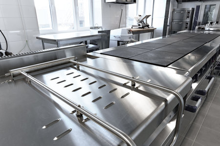 Modern stainless steel kitchen workspace with extensive prep counters and equipment for culinary activitiesの写真素材