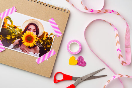 Crafting a scrapbook with a sunflower photo and colorful decoration materials on a light backgroundの写真素材