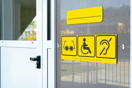 Accessibility signs displayed on the entrance of a public building for individuals with special needsの写真素材